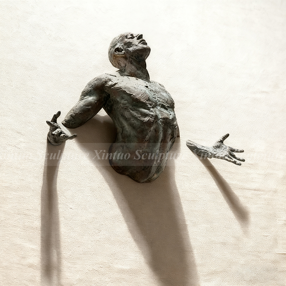 man coming out of the wall sculpture