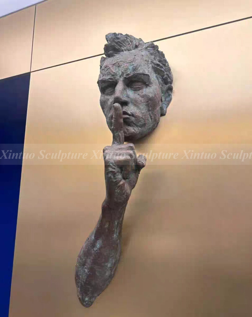 man coming out of the wall sculpture